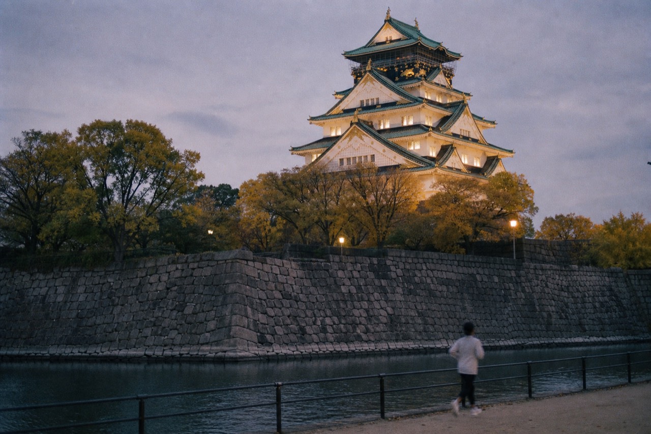 Osaka Castle keep rising above the moat and treeline at dusk