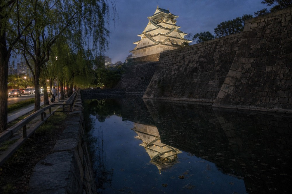 The illuminated white keep of Osaka Castle reflected in the inner moat at night