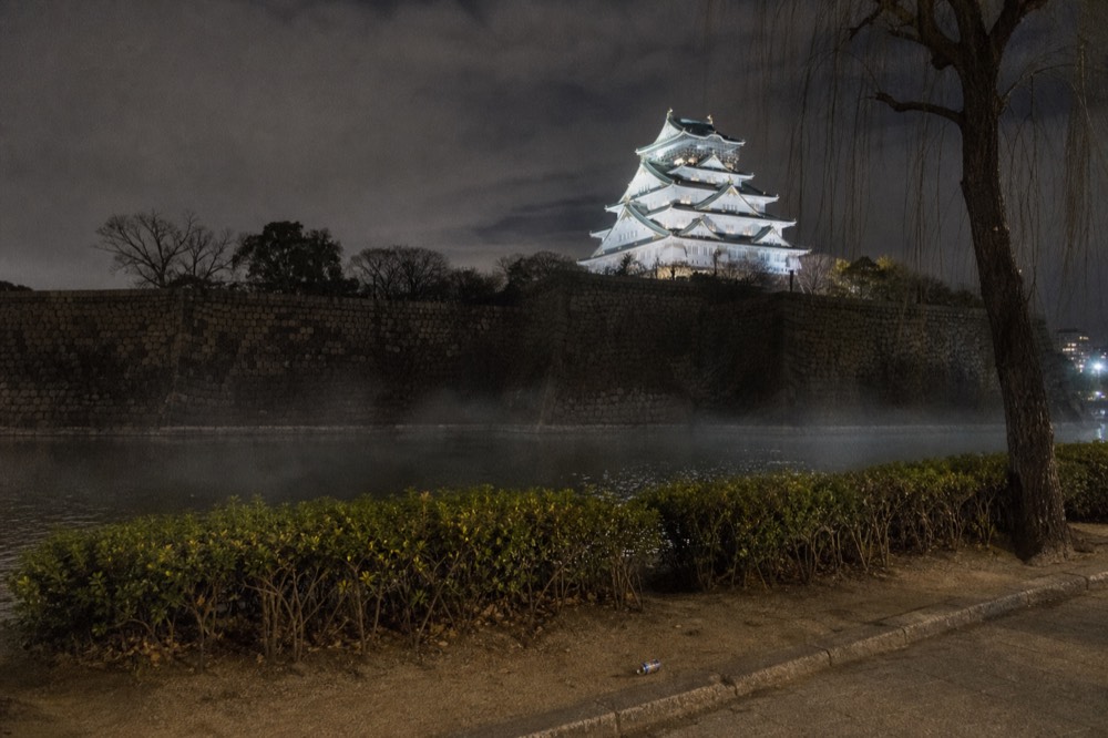 Crowds-free view of the illuminated castle tower from across the outer moat at night