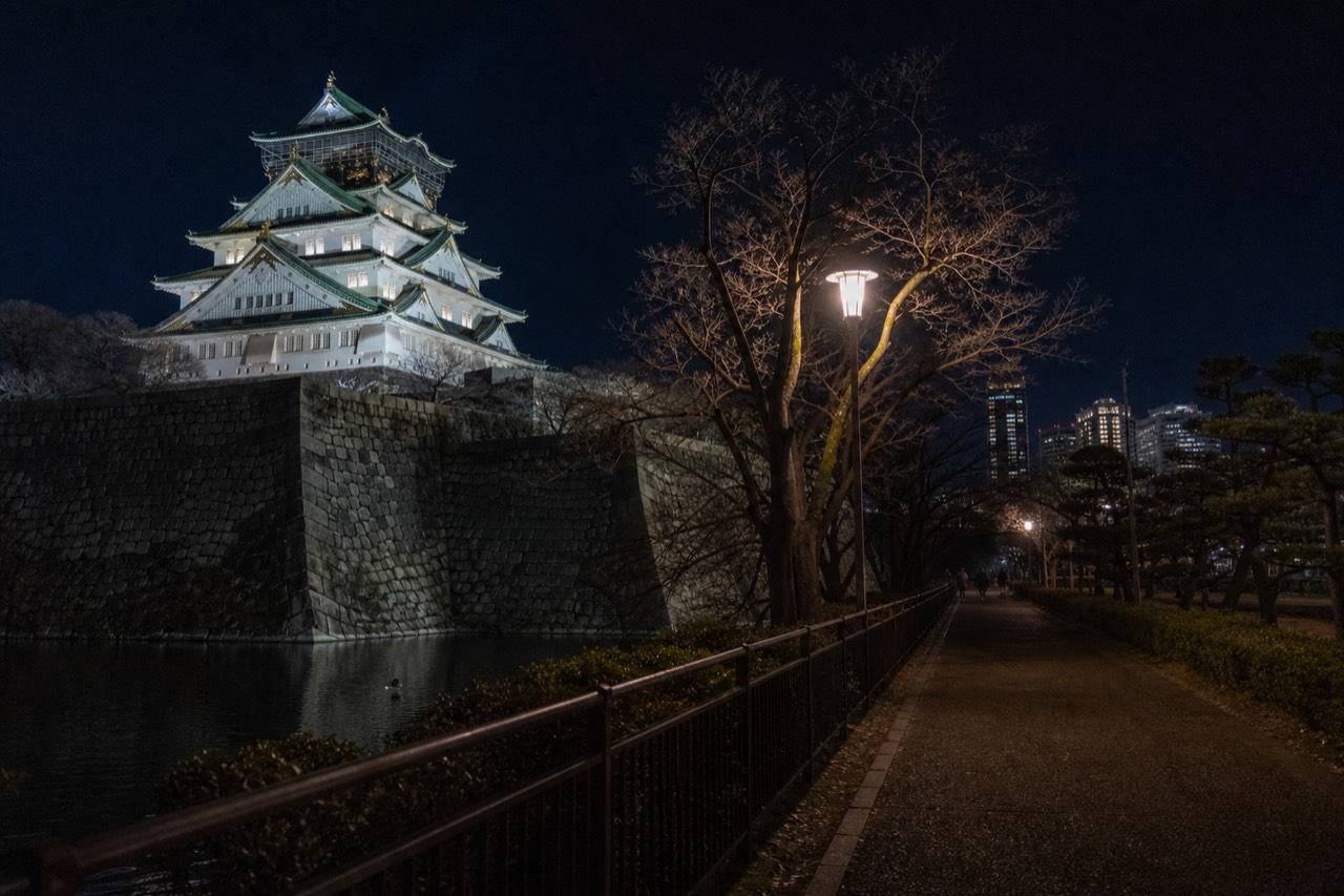 Osaka Castle Main Tower lit up at night above the moat and stone walls
