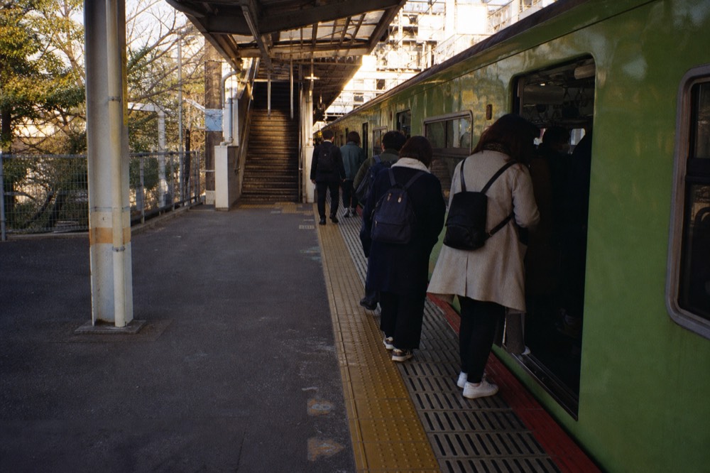 Rail platform in Osaka with a rapid train boarding passengers beside departure signs