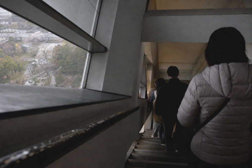 Stone staircase inside a castle museum with visitors climbing between exhibition floors