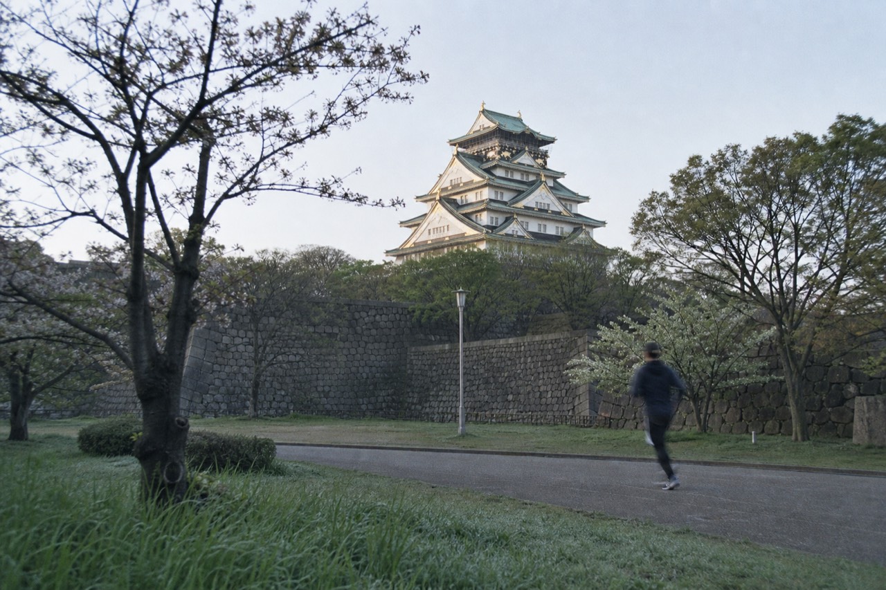 White castle tower rising above stone walls and green trees under a clear sky