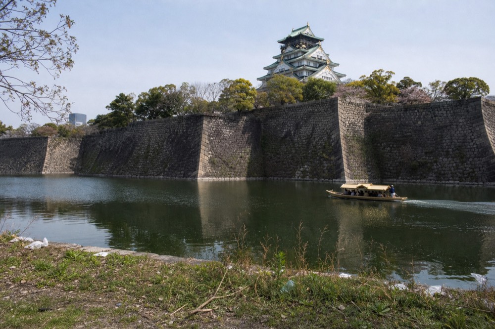 Wide view of Osaka Castle's stone walls and keep above the moat
