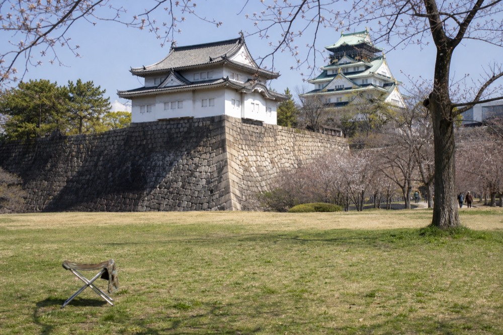 Stone turret and green lawn inside Nishinomaru Garden with the castle tower behind