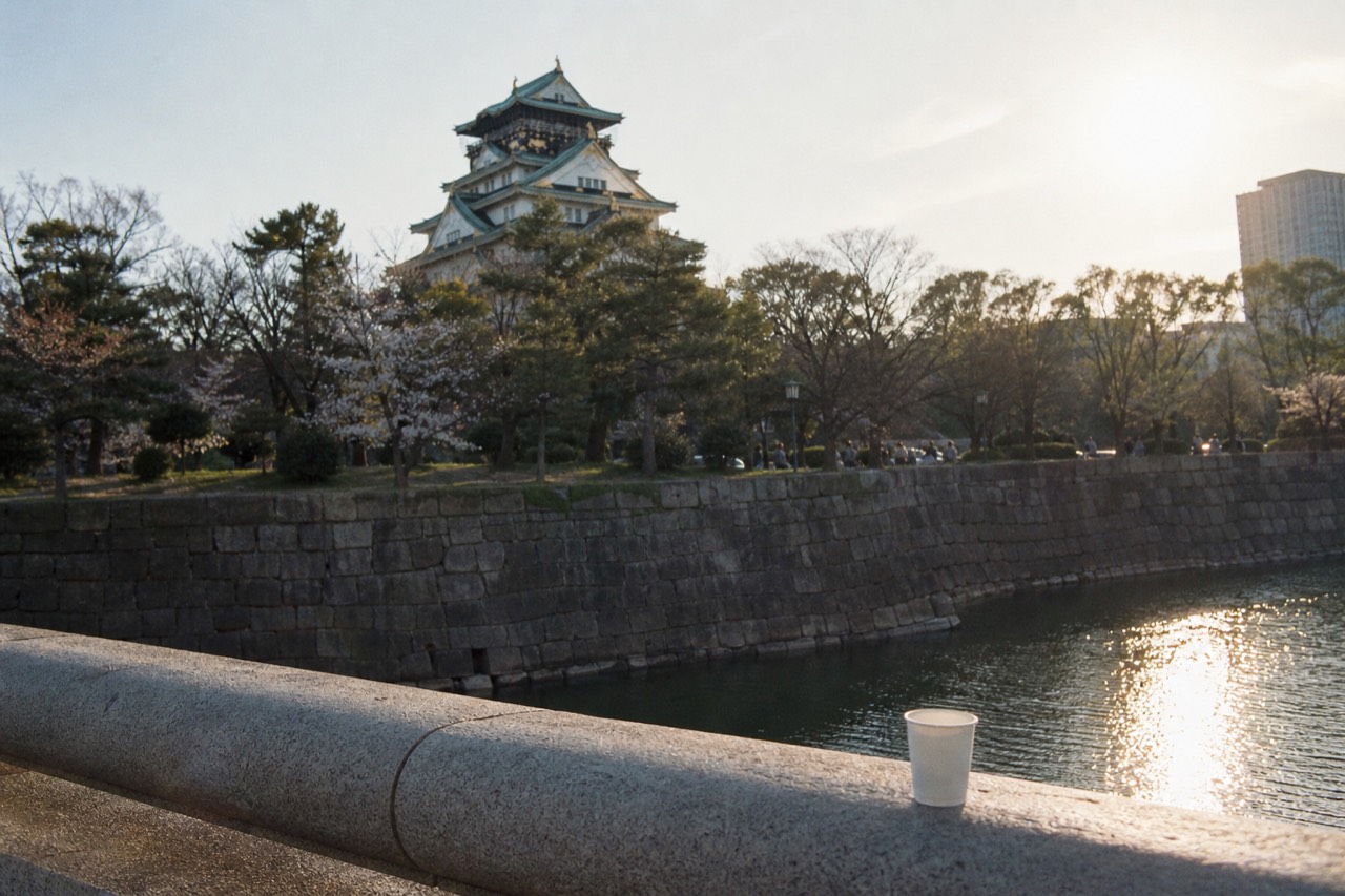 Osaka Castle tower seen from a stone bridge over the moat in late afternoon light