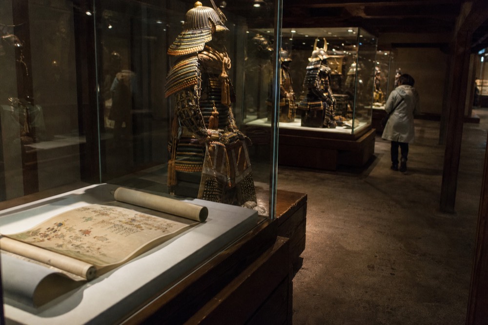 A modern museum gallery displaying samurai armor and historical scrolls