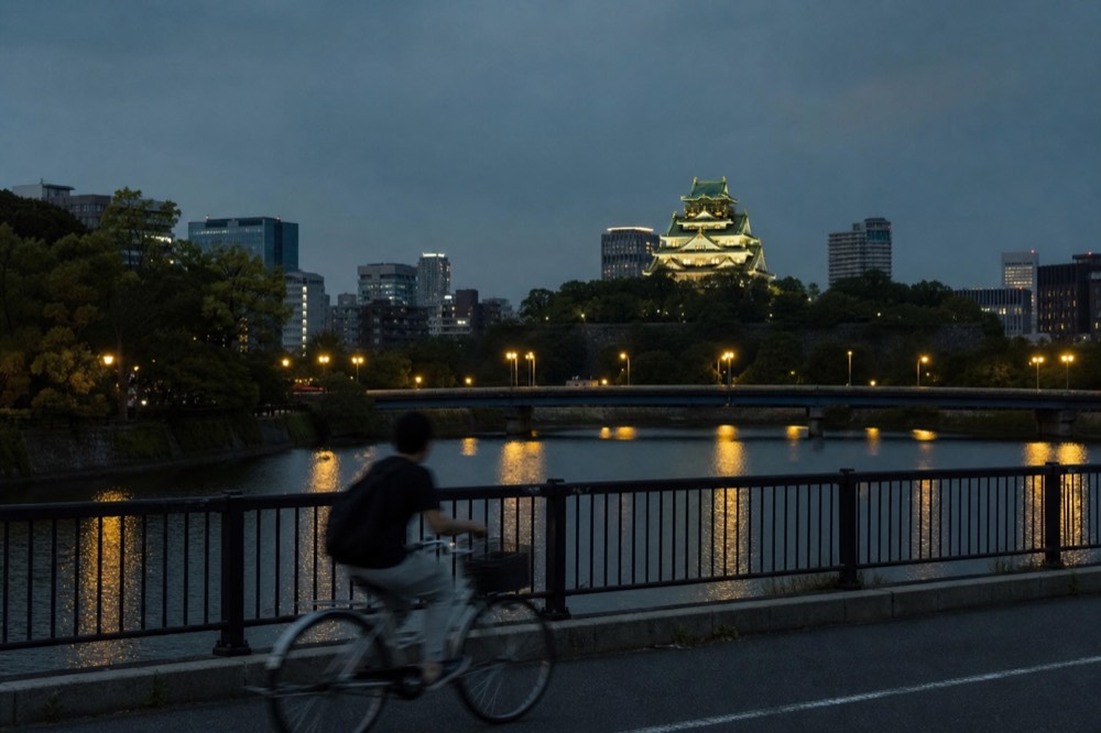 Evening view of illuminated Osaka Castle tower above the office towers of central Osaka