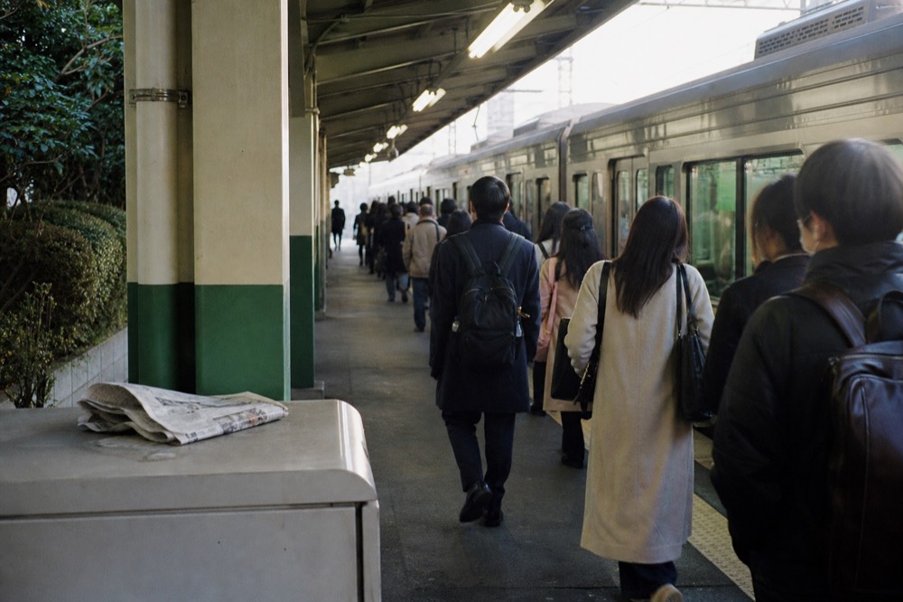 Shinkansen and local trains at a busy Osaka railway platform in the morning
