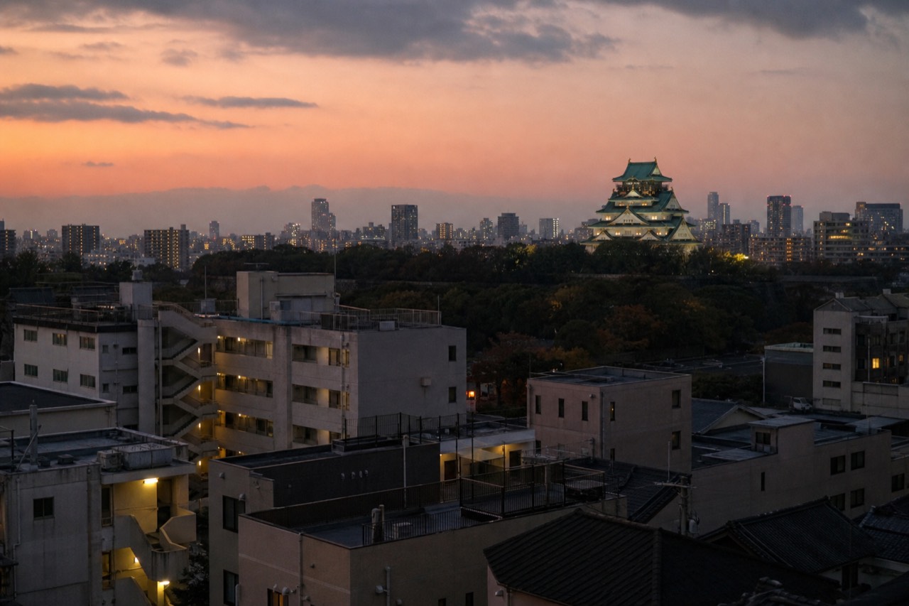 Osaka Castle tower rising above the modern rooftops of Chuo ward at dusk