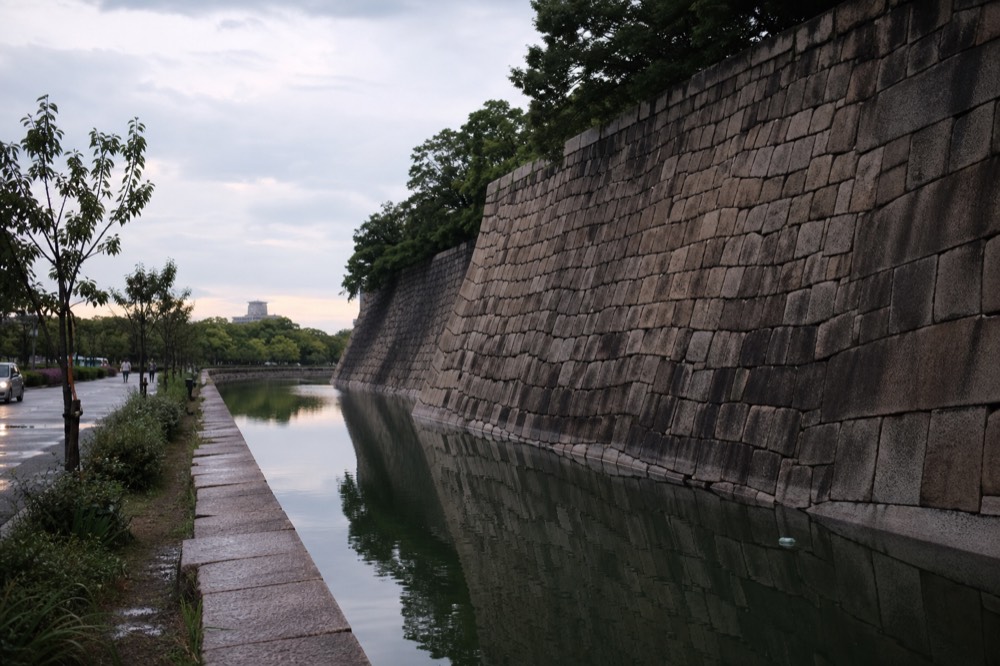 A stone wall of massive fitted granite blocks rising above a water moat