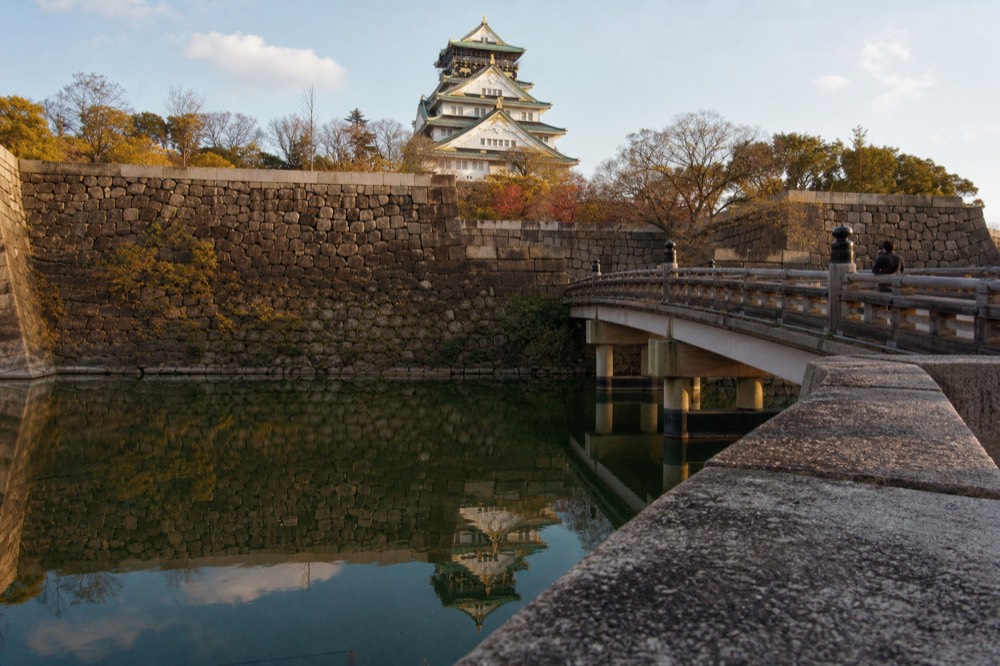The Aoyamon gate and the stone bridge over the inner moat reflecting the castle tower on a sunny afternoon