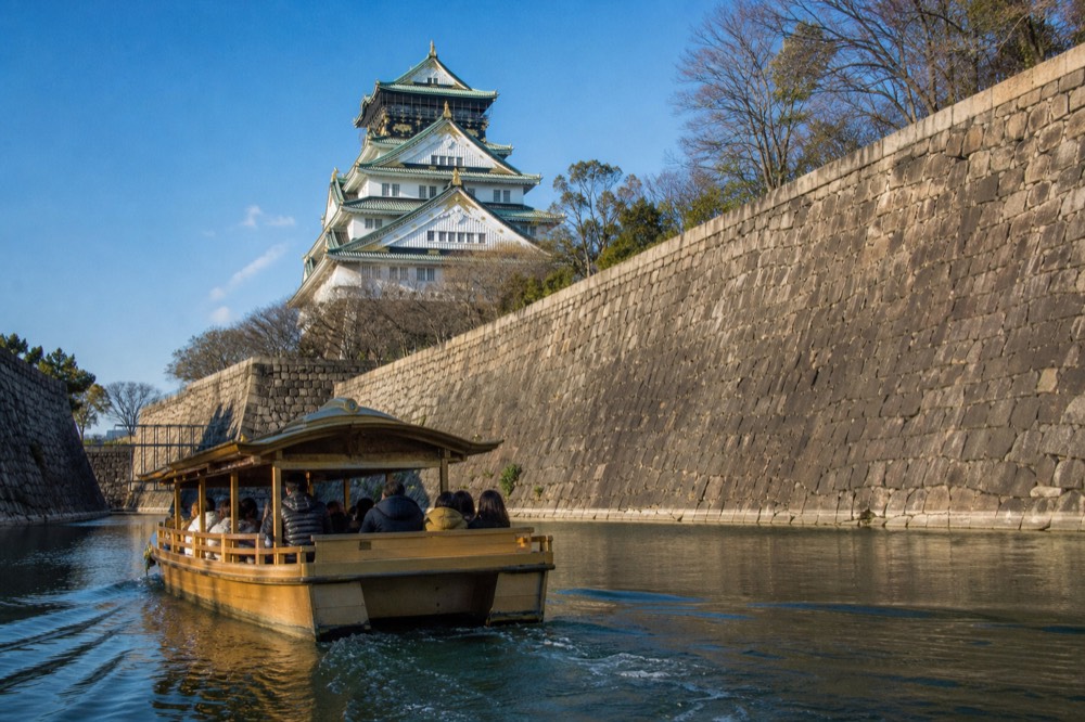 The Gozabune boat on the inner moat of Osaka Castle with the tower and stone walls in the background under a blue sky