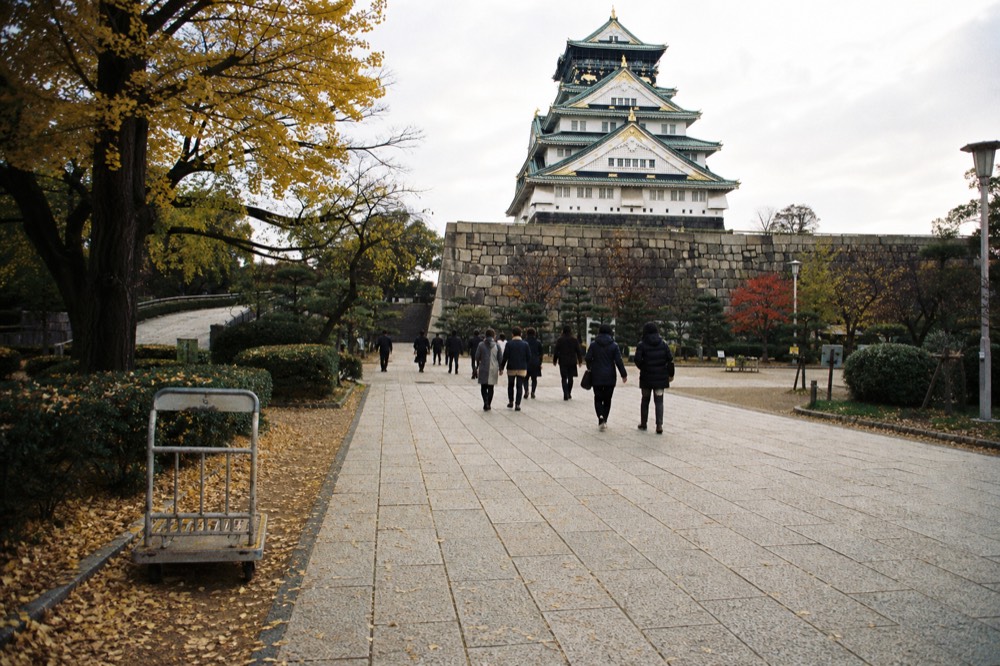 The plaza inside the Honmaru with the castle tower rising in the background and visitors walking on the stone pavement