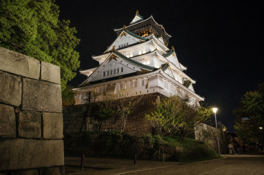 The tower's golden shachi ornaments visible against the night sky, illuminated by the floodlights from below