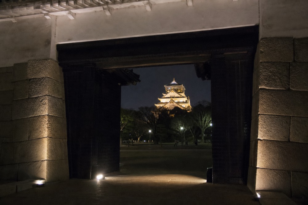 The Otemon gate illuminated at night, with the tower visible through the gate's central opening