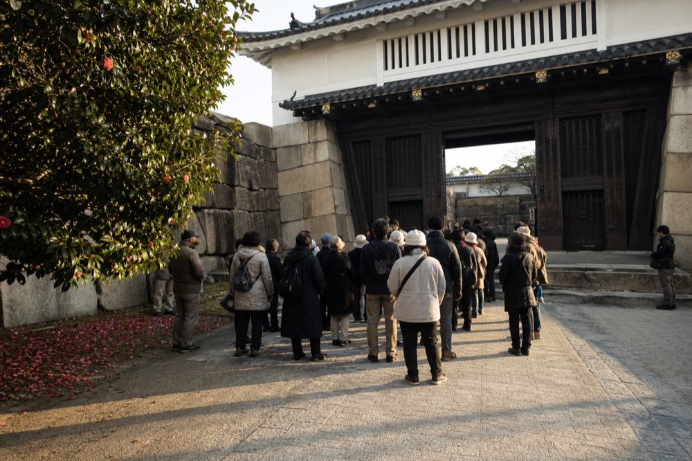 A group of visitors listening to a guide near the Otemon gate of Osaka Castle.