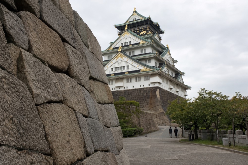 The stone walls of Osaka Castle showing the nozurazumi masonry technique, with the tower in the background