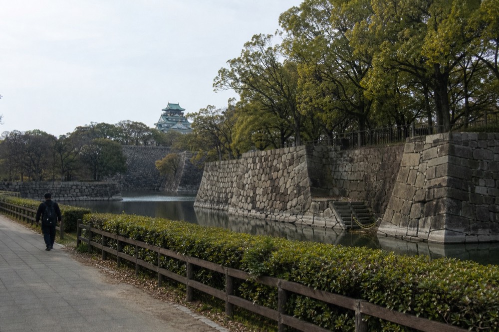 Wide shot of the inner moat and stone walls with the tower in the distance