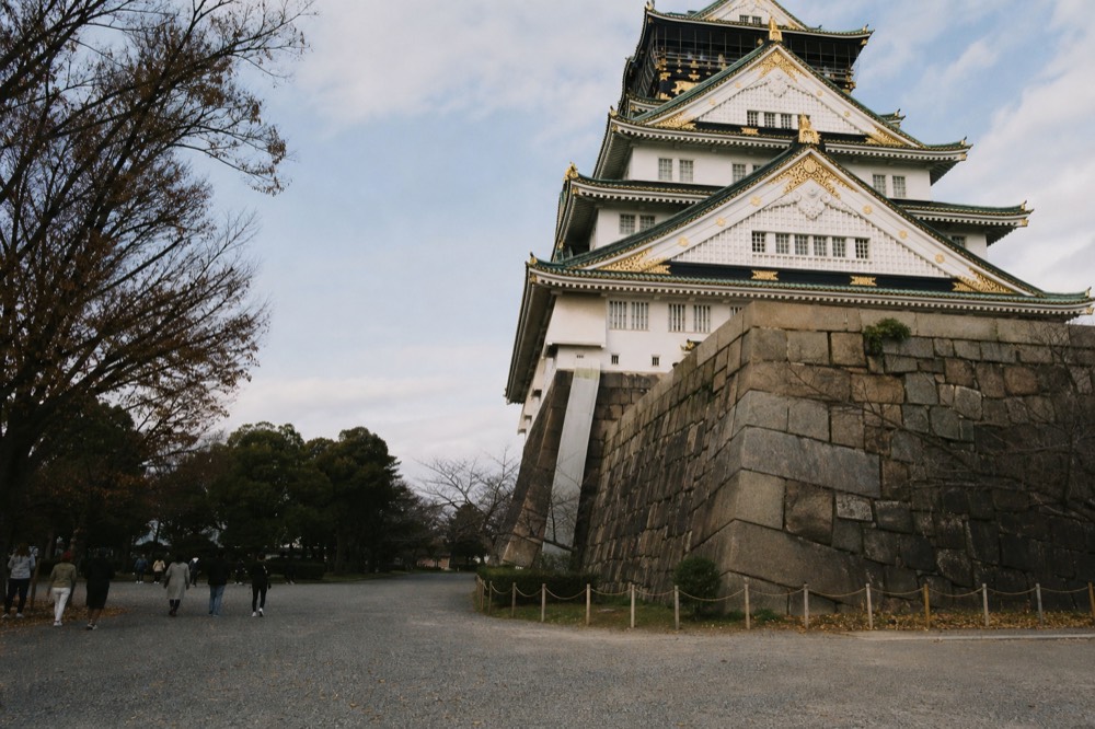 White plastered walls, green copper roofs and gold trim define the Main Tower, seen across the open Honmaru plaza.