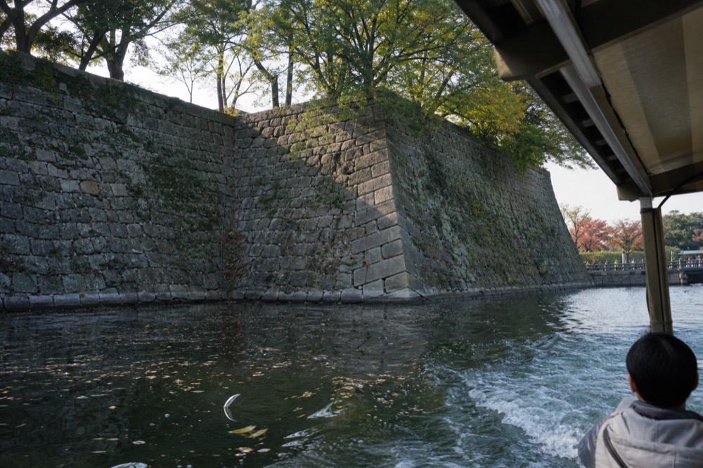 Wide moat and high stone embankment surrounding the castle grounds in daylight
